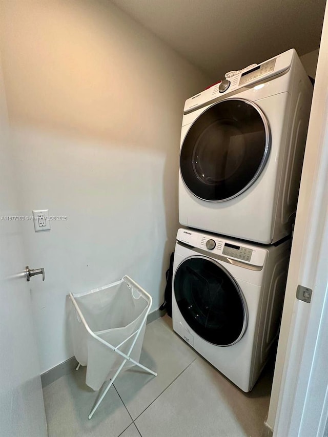 laundry area with stacked washer / drying machine and light tile patterned flooring