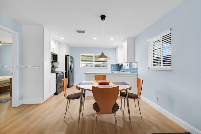 dining room featuring sink, light hardwood / wood-style flooring, and plenty of natural light