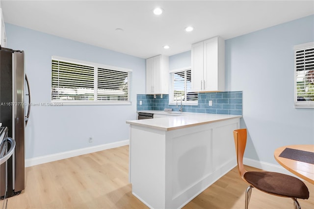 kitchen featuring sink, backsplash, kitchen peninsula, light hardwood / wood-style floors, and white cabinets