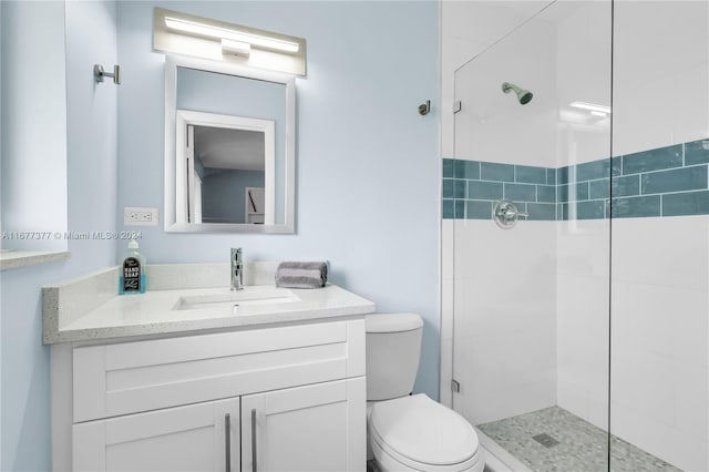 bathroom with toilet, vanity, and tiled shower