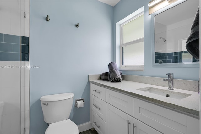 bathroom featuring vanity, a tile shower, and toilet