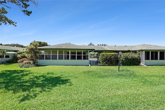 rear view of property featuring a yard and a sunroom