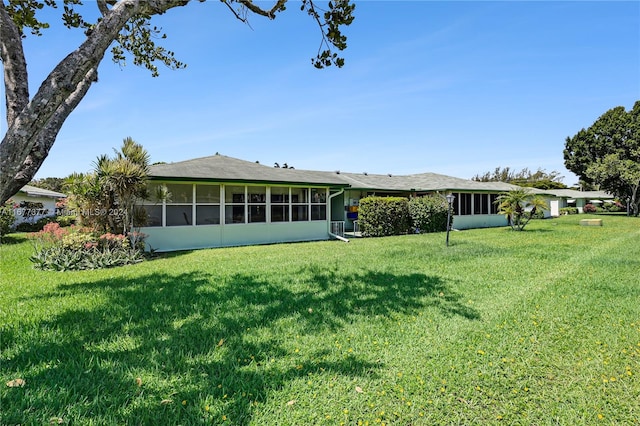 rear view of property featuring a yard and a sunroom