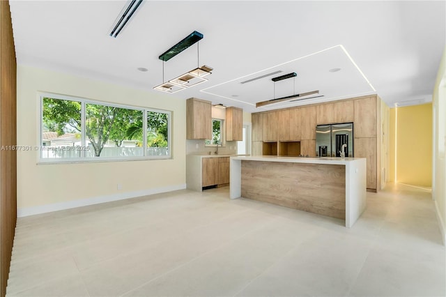 kitchen featuring stainless steel refrigerator with ice dispenser, decorative light fixtures, and a kitchen island