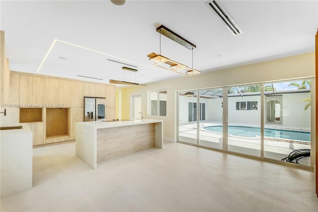 kitchen with sink, stainless steel fridge, black electric stovetop, a kitchen island, and decorative light fixtures