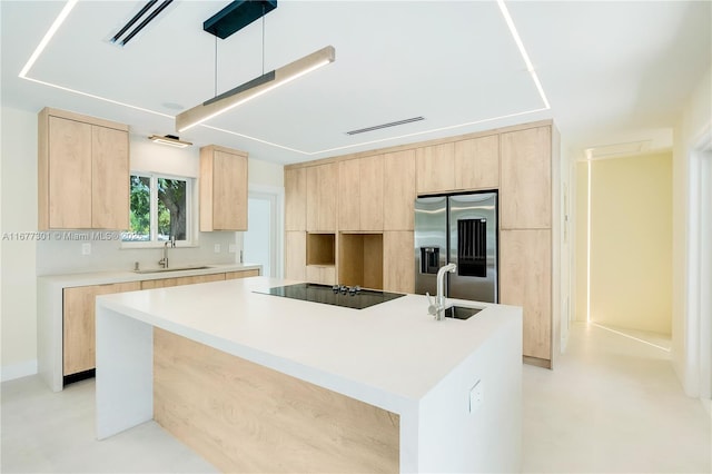 kitchen with stainless steel refrigerator with ice dispenser, black electric cooktop, sink, and a center island with sink