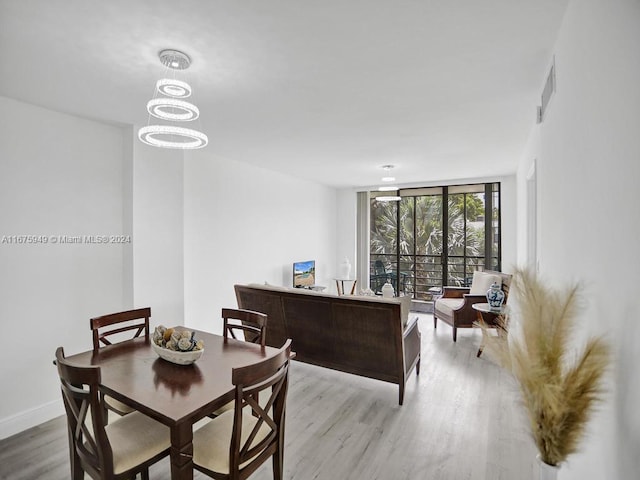 dining room with an inviting chandelier, expansive windows, and light wood-type flooring