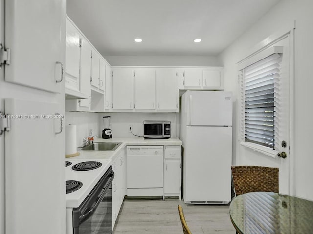 kitchen featuring sink, white cabinets, light wood-type flooring, and white appliances