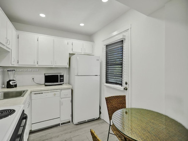 kitchen with white appliances, sink, light wood-type flooring, and white cabinets