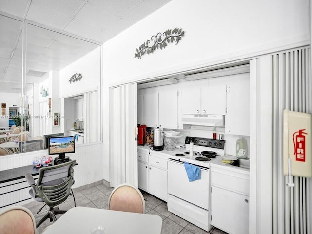 kitchen featuring white cabinets, light tile patterned flooring, and electric stove