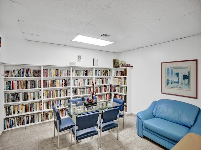 living area featuring a drop ceiling and light tile patterned floors