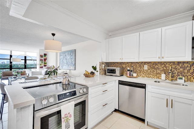 kitchen with kitchen peninsula, sink, white cabinets, decorative light fixtures, and appliances with stainless steel finishes