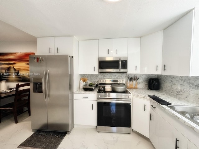 kitchen featuring stainless steel appliances, white cabinets, and backsplash