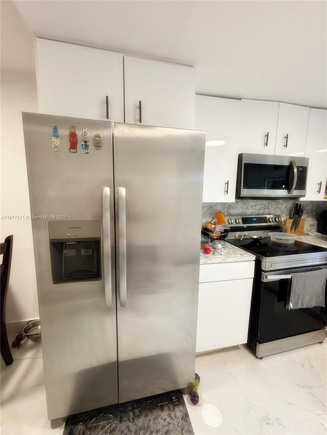 kitchen featuring tasteful backsplash, white cabinets, and appliances with stainless steel finishes