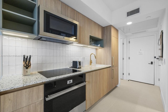 kitchen featuring sink, appliances with stainless steel finishes, light stone counters, and tasteful backsplash