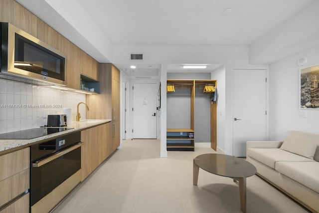 kitchen featuring light stone counters, stainless steel appliances, and backsplash