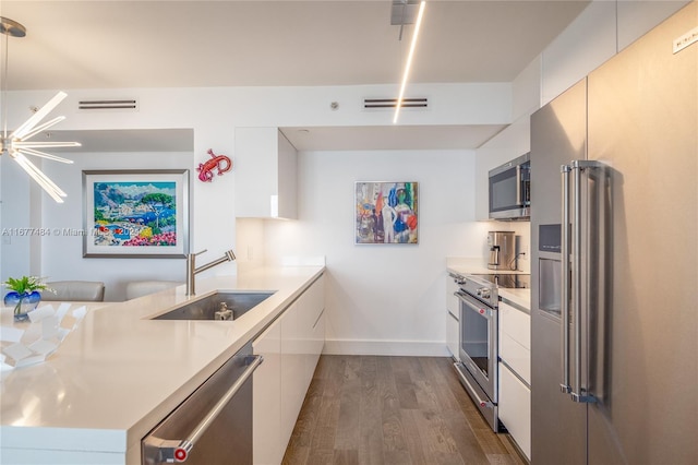 kitchen with kitchen peninsula, stainless steel appliances, wood-type flooring, sink, and white cabinets