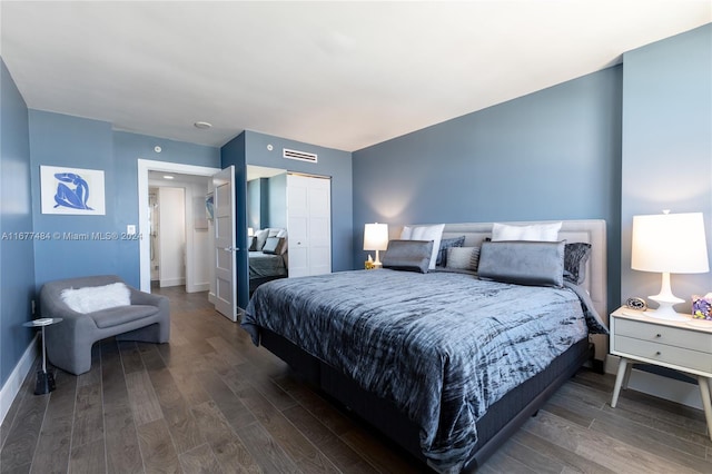bedroom featuring wood finished floors, baseboards, visible vents, and a closet