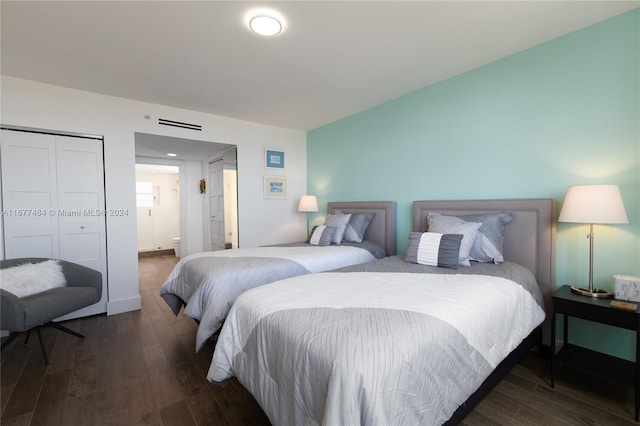 bedroom featuring dark wood-style floors, visible vents, and connected bathroom