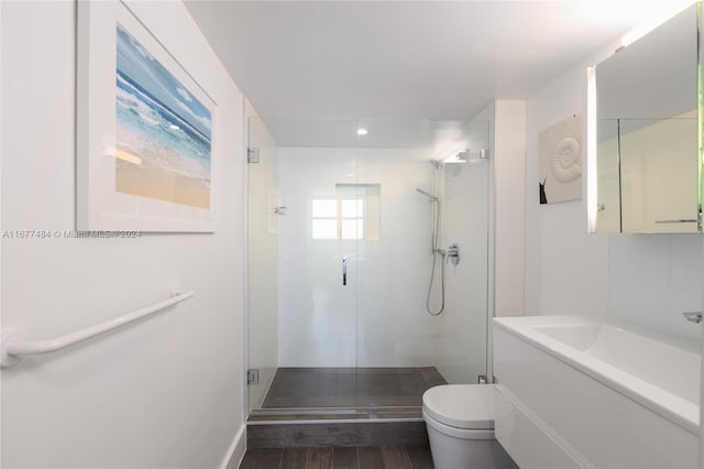 bathroom with vanity, wood finished floors, toilet, and a stall shower