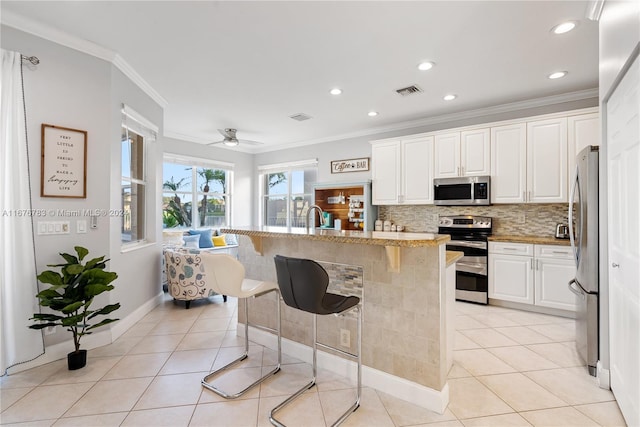 kitchen with appliances with stainless steel finishes, a kitchen island with sink, and white cabinetry