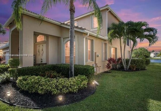 property exterior at dusk featuring a lawn