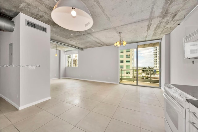 empty room with light tile patterned floors and an inviting chandelier