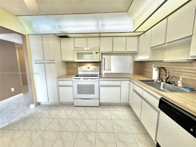 kitchen with white appliances, tasteful backsplash, sink, white cabinetry, and light tile patterned floors