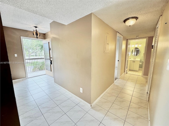 hall with a textured ceiling and light tile patterned floors