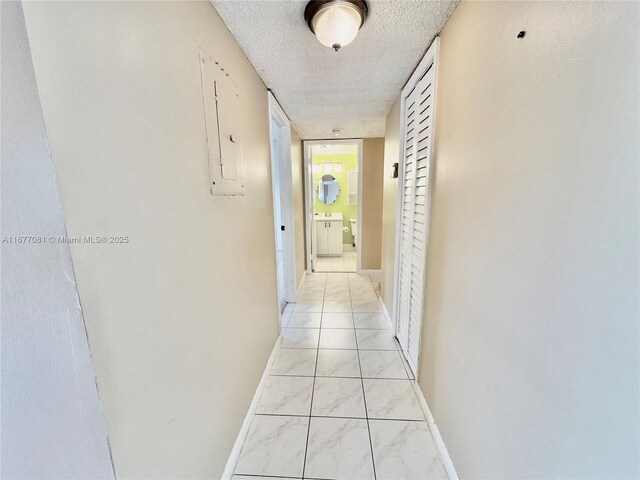 corridor featuring a textured ceiling, electric panel, and light tile patterned floors