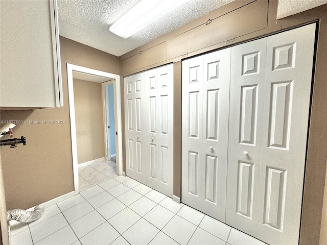 corridor featuring light tile patterned flooring and a textured ceiling