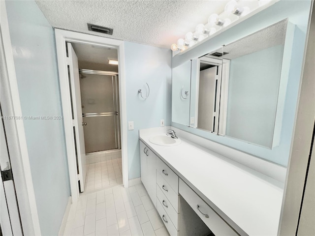 bathroom featuring vanity, tile patterned flooring, a textured ceiling, and walk in shower