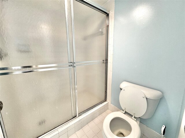 bathroom with tile patterned flooring, toilet, and an enclosed shower