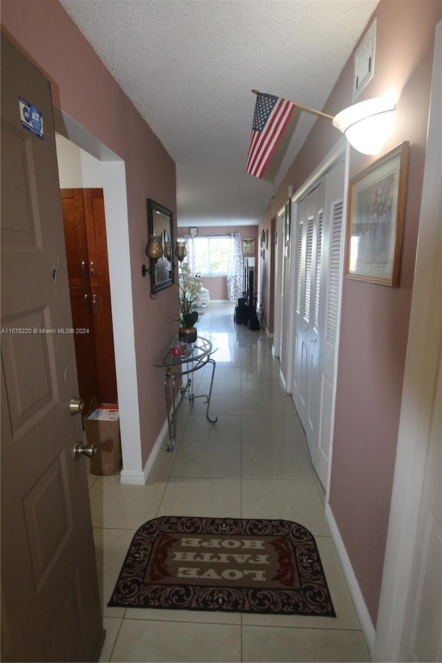 hall with light tile patterned floors and a textured ceiling