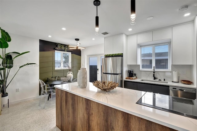 kitchen featuring white cabinetry, decorative light fixtures, stainless steel appliances, and sink