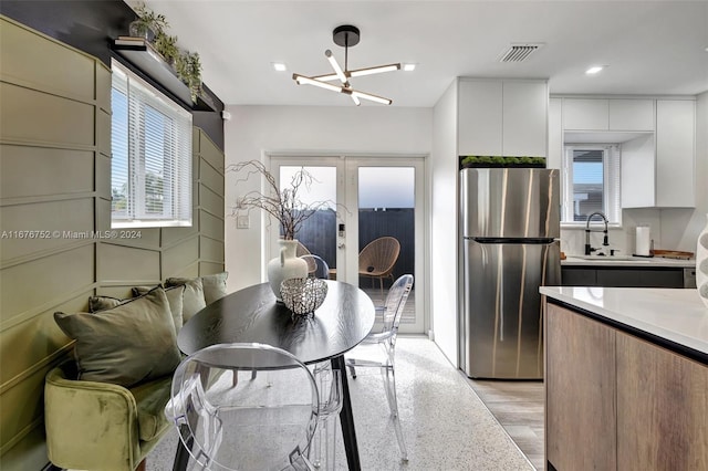 dining space with french doors, light hardwood / wood-style flooring, sink, and a chandelier