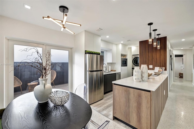 kitchen featuring white cabinets, an inviting chandelier, stainless steel appliances, decorative light fixtures, and a center island