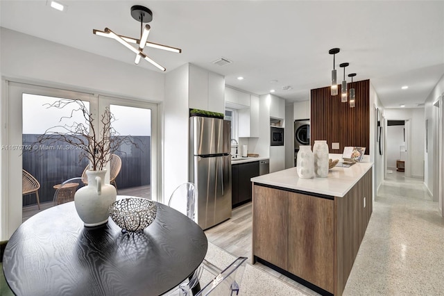 kitchen featuring sink, a kitchen island, stainless steel fridge, pendant lighting, and white cabinets