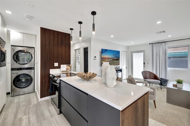 kitchen featuring stacked washer and dryer, stainless steel range with electric stovetop, a center island, decorative light fixtures, and light hardwood / wood-style floors