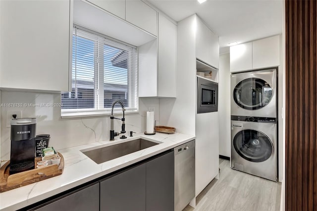 washroom featuring stacked washer and dryer, sink, and light hardwood / wood-style floors