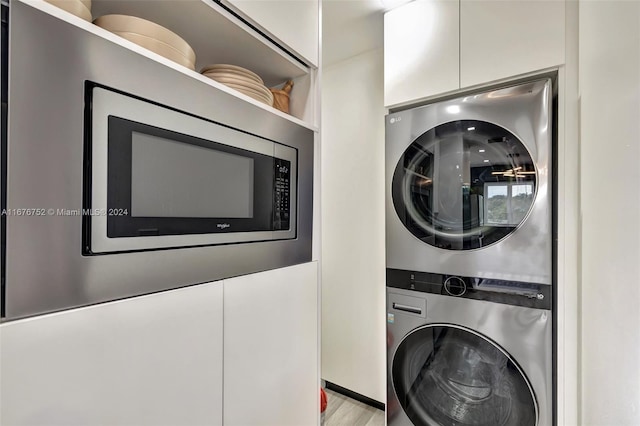 clothes washing area featuring light hardwood / wood-style floors and stacked washer and clothes dryer