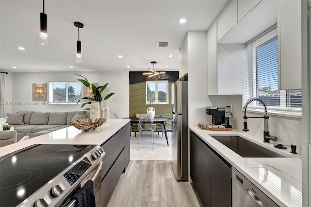 kitchen with sink, decorative light fixtures, stainless steel appliances, and light hardwood / wood-style floors