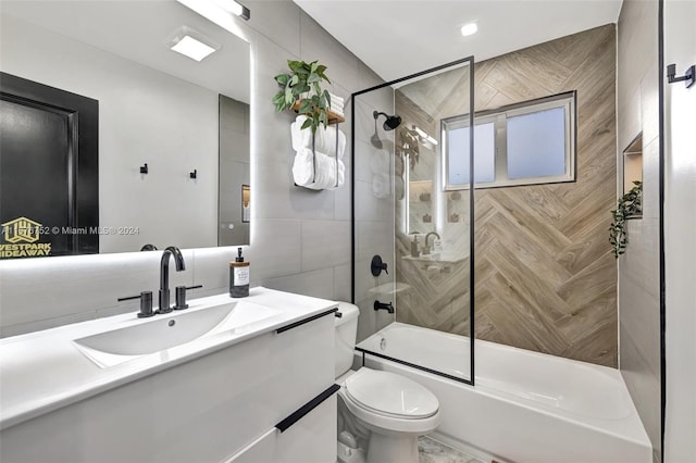 full bathroom featuring tile walls, vanity, shower / bath combination with glass door, and toilet