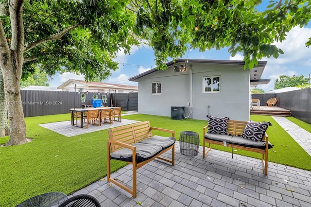 back of property with central AC, an outdoor living space, a patio, and a lawn