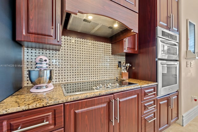 kitchen featuring appliances with stainless steel finishes, decorative backsplash, light stone countertops, and exhaust hood