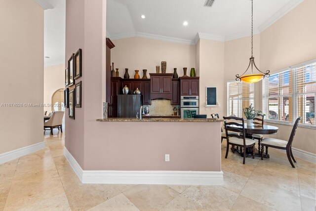 kitchen with kitchen peninsula, appliances with stainless steel finishes, stone counters, pendant lighting, and crown molding