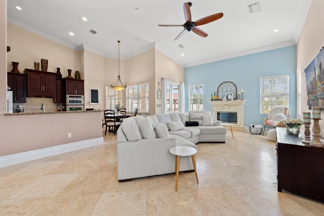 living room with a wealth of natural light, ornamental molding, and a high ceiling