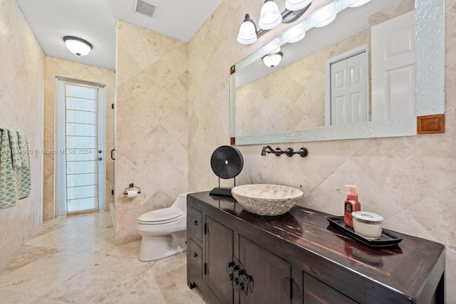 bathroom with tile walls, vanity, and toilet