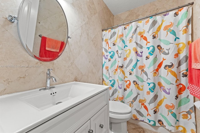 bathroom featuring tile walls, toilet, vanity, a shower with curtain, and tile patterned floors