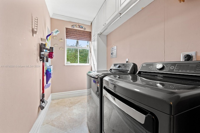 washroom with crown molding, washer and clothes dryer, light tile patterned floors, and cabinets